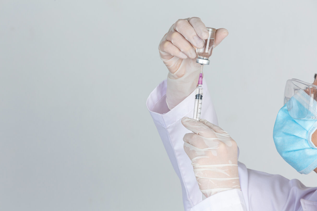Young doctor is  holding  hypodermic syringe with  vaccine vial